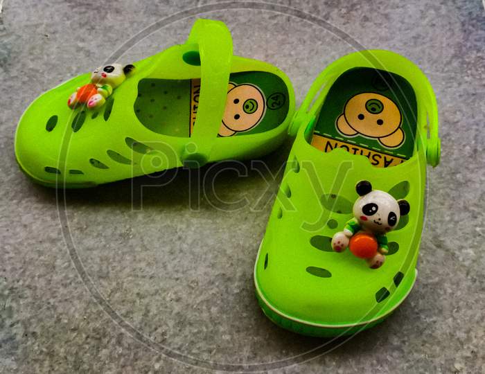 A vibrant green coloured pair of footwear of a baby.