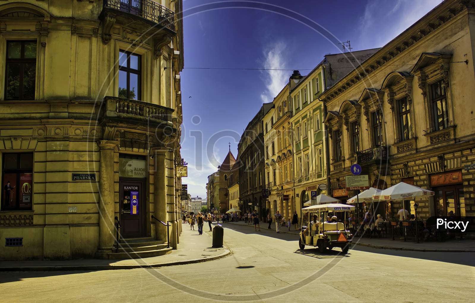 Krakow, Poland - June 08, 2014: A Wide Angle Shot Of Polish Street And Architecture And An Open City Tour Car With Tourists