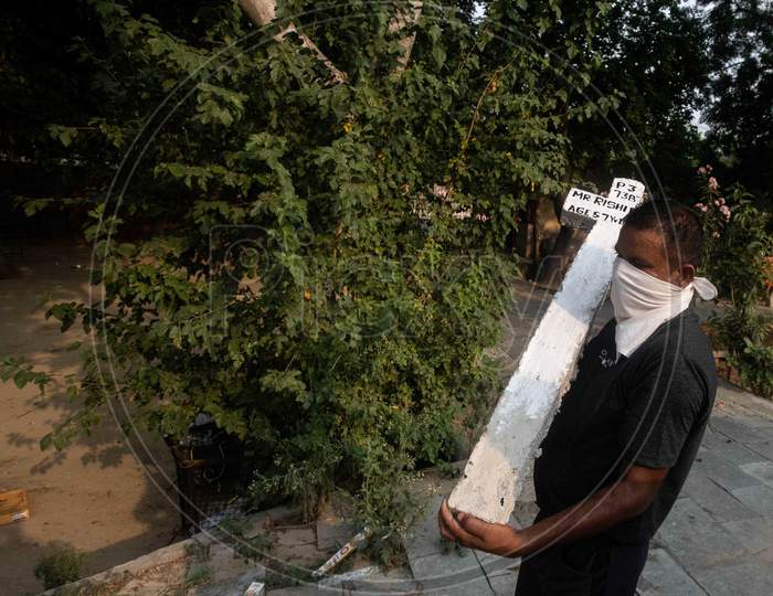 A Cemetery Worker Carries A Cross  At Mangolpuri Cemetery Amid The Covid-19 Pandemic On July 1, 2020 In New Delhi, India.