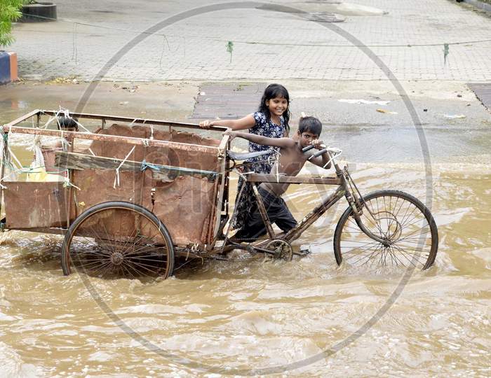 Rag picker children carrying a cart through a waterlogged street