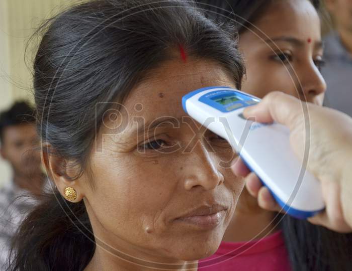 A health worker checks the body temperature of a Tourist