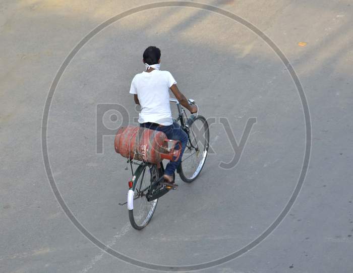 A man carry a LPG Cylinder on his by cycle on deserted road during the nationwide lockdown