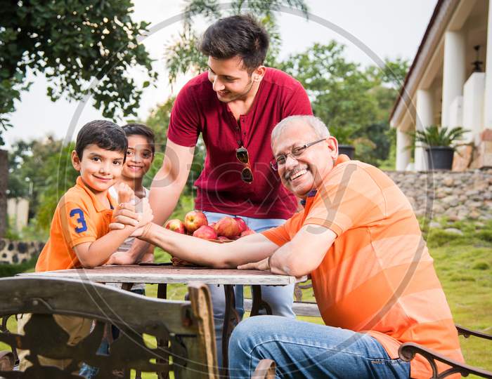 Indian/Asian kid and Grandfather Arm wrestling and having fun