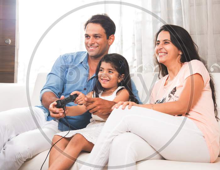 Indian family watching television / Tv while sitting on sofa