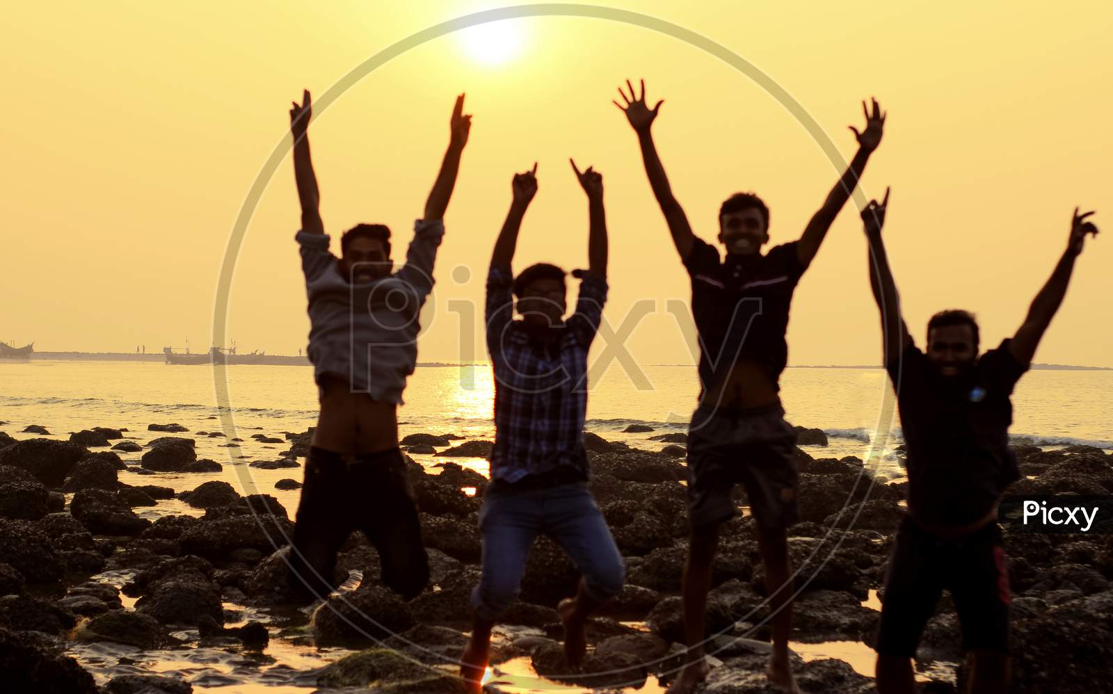 A Group By Four Young Man Jumping Activity During Sunset At Sea Beach .