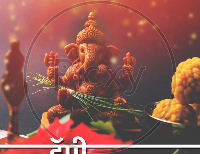 Happy Ganesh Chaturthi Greeting Card showing photograph of lord ganesha idol with pooja or puja thali, bundi laddu/modak, durva
