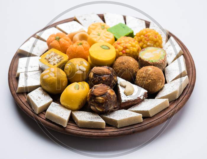 Indian sweets served in silver or wooden plate. variety of Peda, burfi, laddu in decorative plate, selective focu