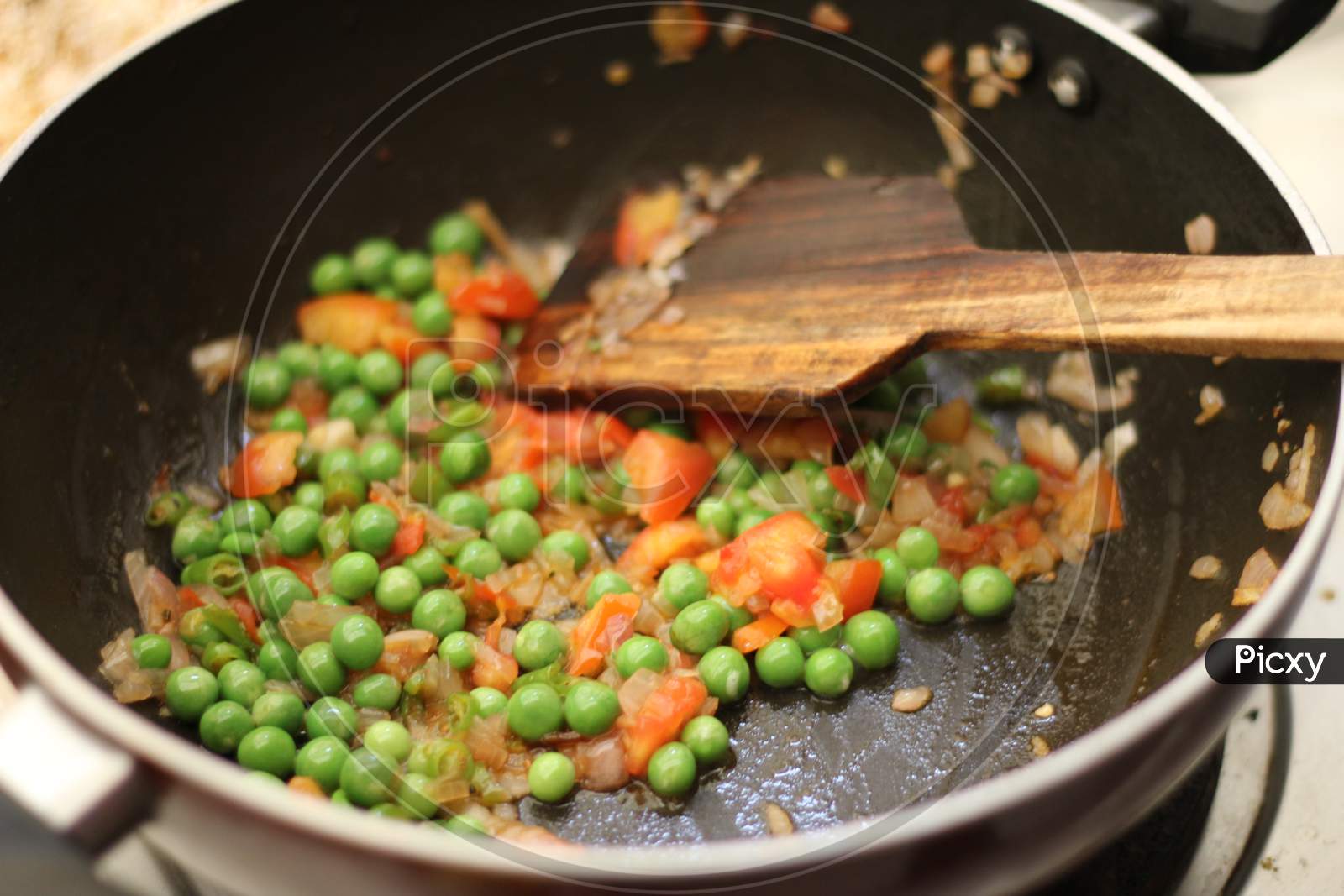 Cooking vegetables peas in a fry pan.