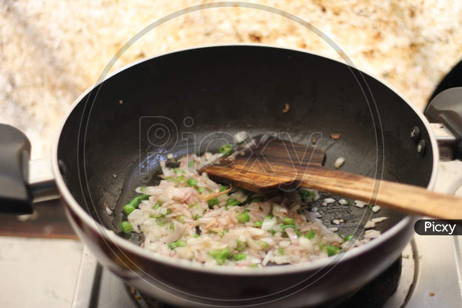 Cooking vegetables, onion and green chillies in a fry pan