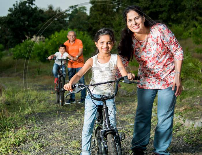 Indian girl learning to ride on bicycle, balancing. Grandma helping her