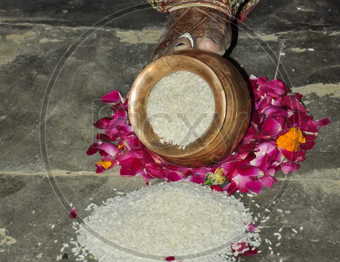 Indian Bride Pushing Pot Filled With Rice In Wedding.