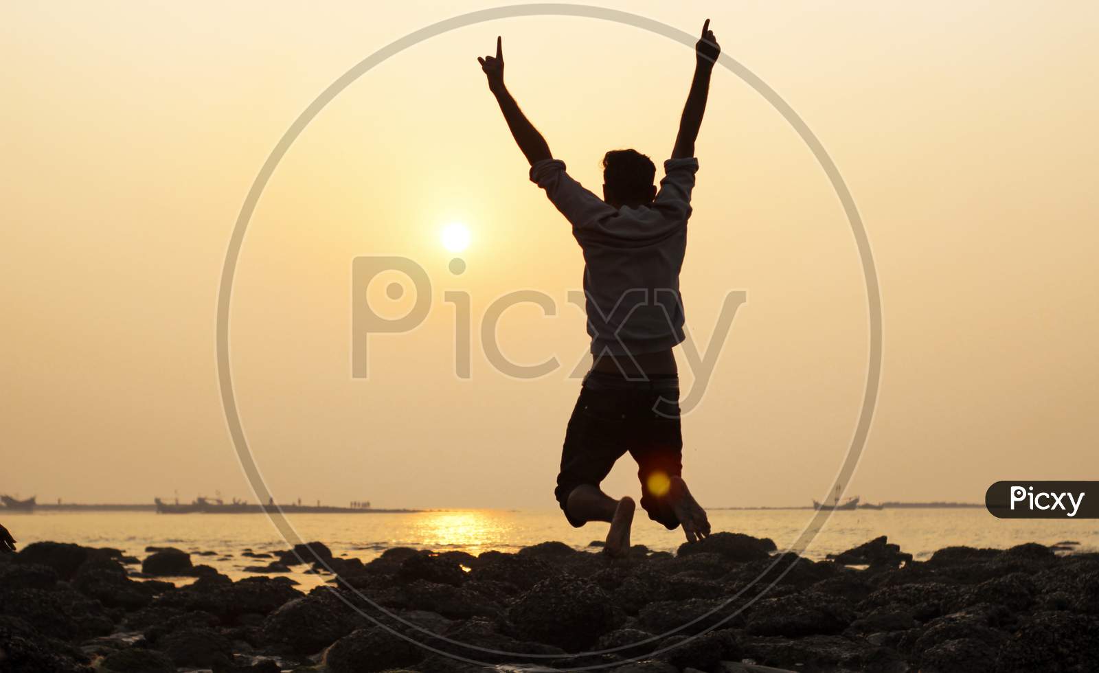 A Young Man Jump And Expressed Hands Up During Nature Sunset At Sea Beach .
