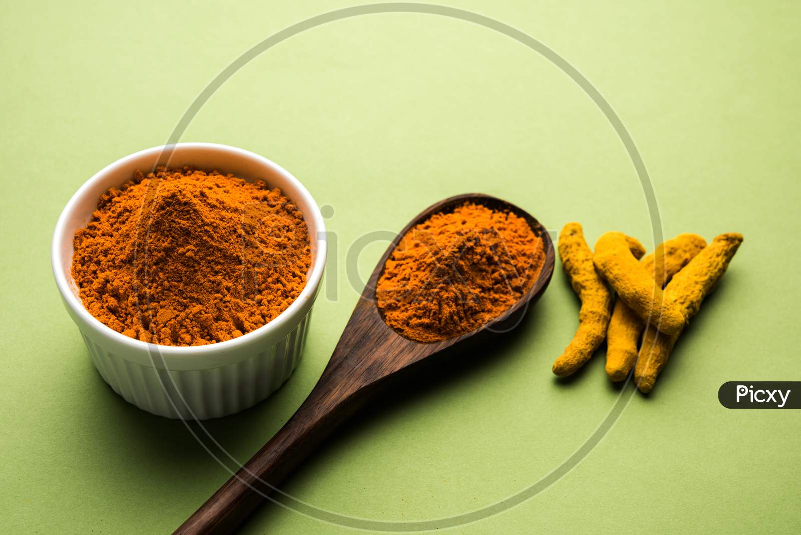 Turmeric or Haldi powder in bowl over colourful background