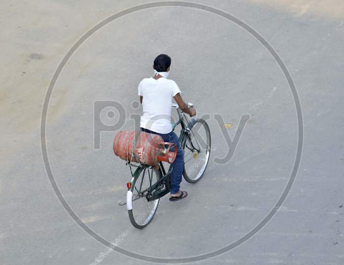 A man carry a LPG Cylinder on his by cycle on deserted road during the nationwide lockdown