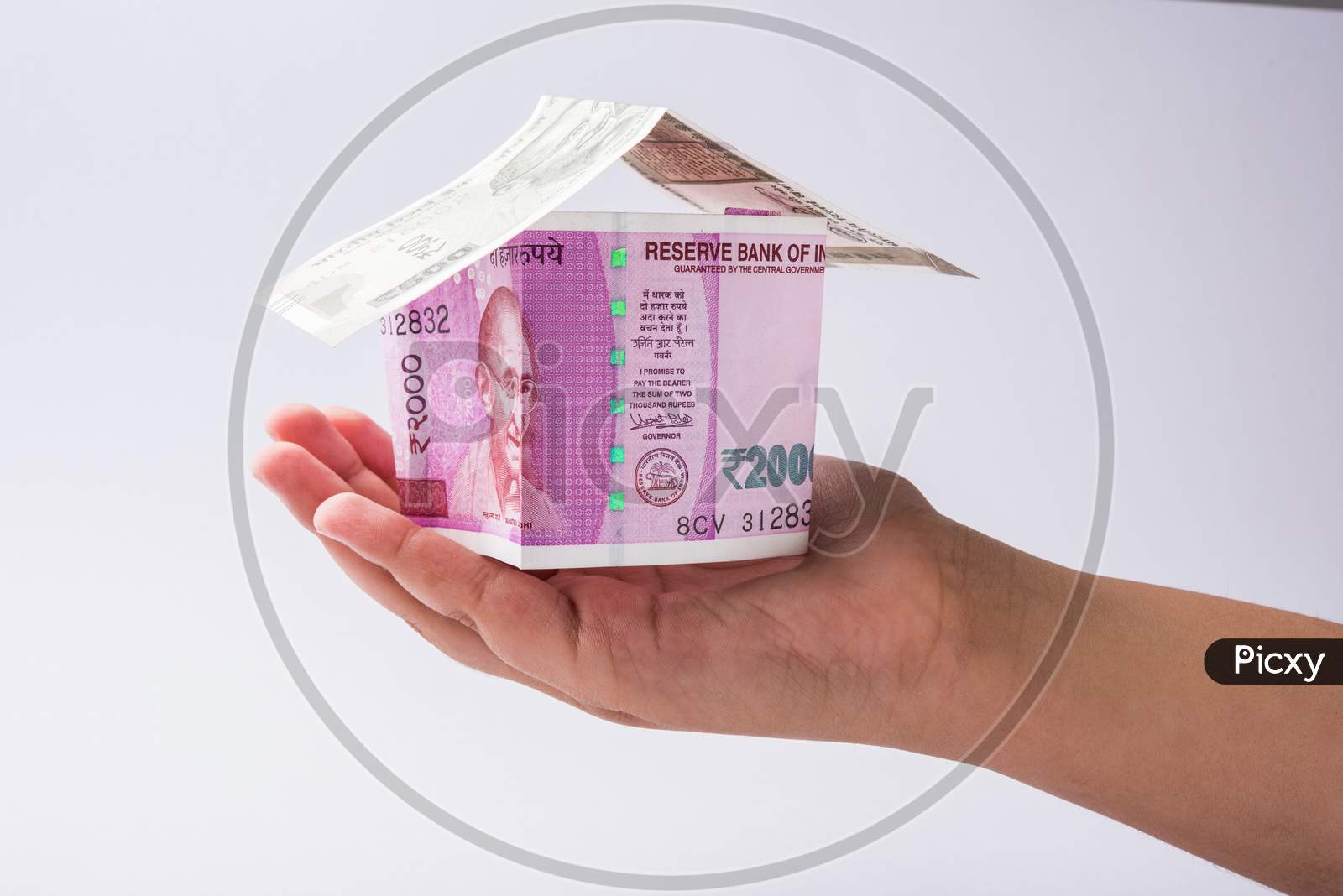 Hand holding 3D Model house using Indian currency
