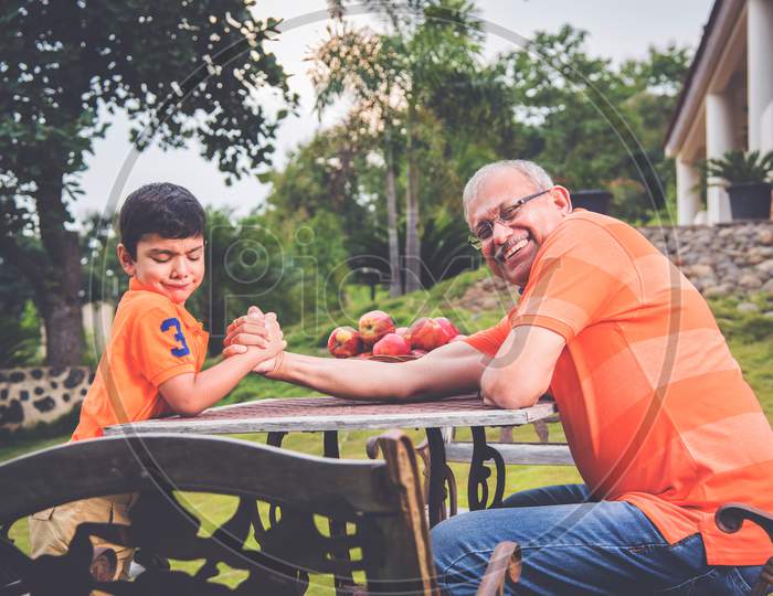Indian/Asian kid and Grandfather Arm wrestling and having fun