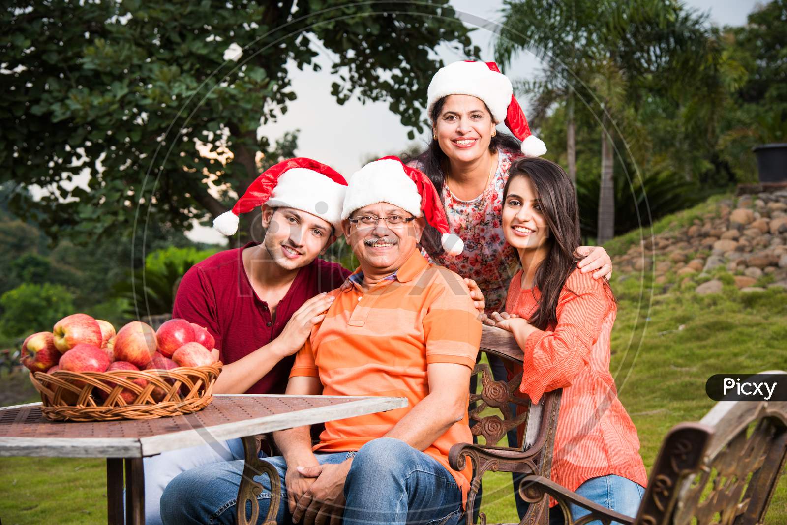 Portrait of Happy Indian/Asian Family celebrating christmas / Xmas while sitting on Lawn chair, outdoor