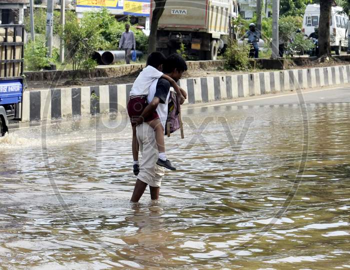 A man carrying his child on his shoulder in a water logging street