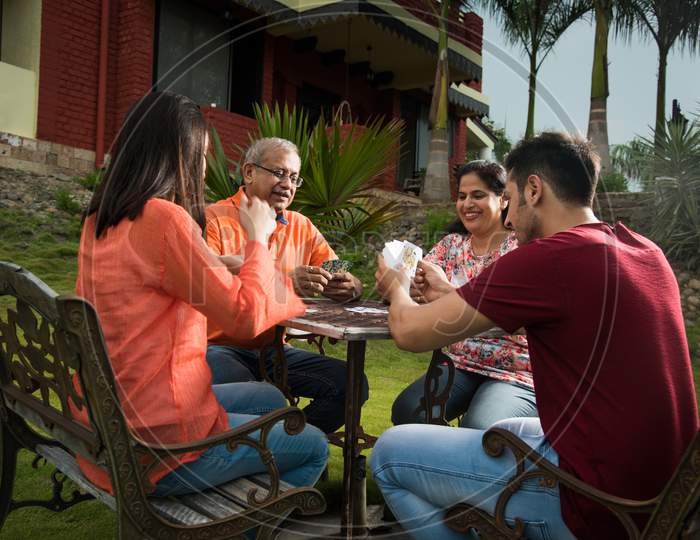 Indian family playing cards while sitting outdoor
