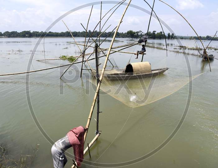 Villagers  indulge in fishing in the flooded Pobitora Wildlife Sanctuary,