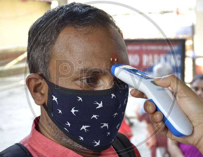 A health worker checks the body temperature of a Tourist