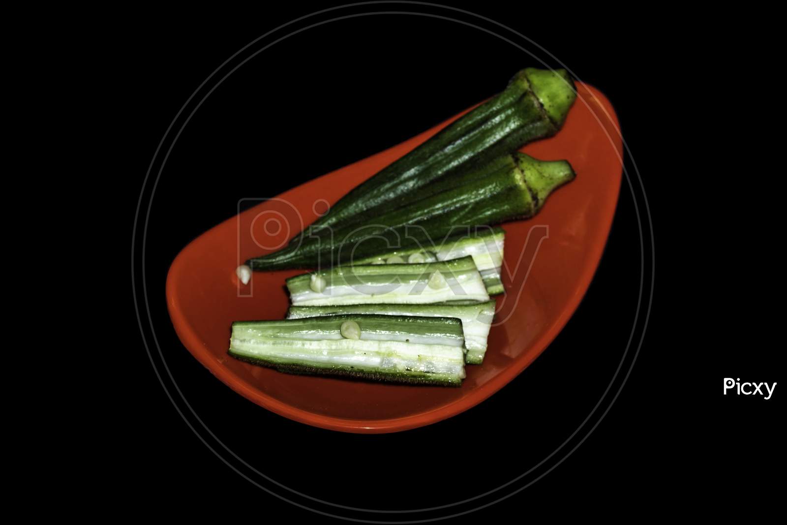 Red Plate of Lady Finger seed on Center Isolated in black background