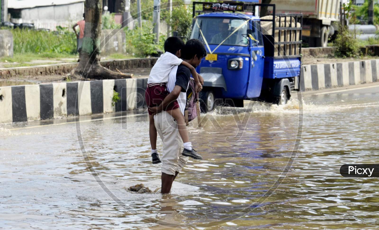 A man carrying his child on his shoulder in a water logging street
