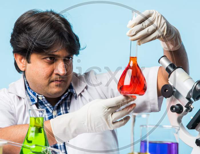 Indian male scientist or doctor or science student experimenting