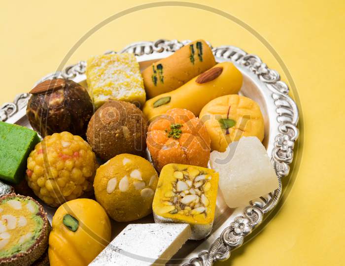 Indian sweets served in silver or wooden plate. variety of Peda, burfi, laddu in decorative plate, selective focu