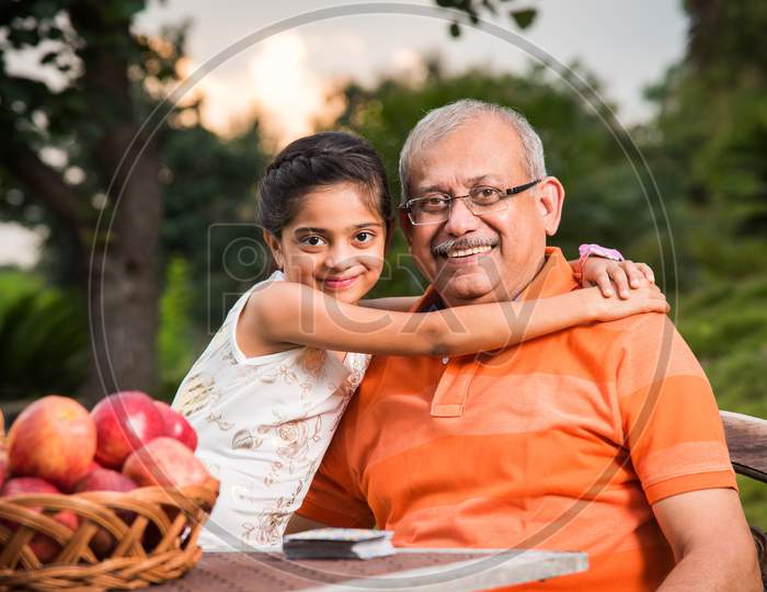 Portrait of Happy Indian/Asian Kids and grandfather sitting on lawn chair