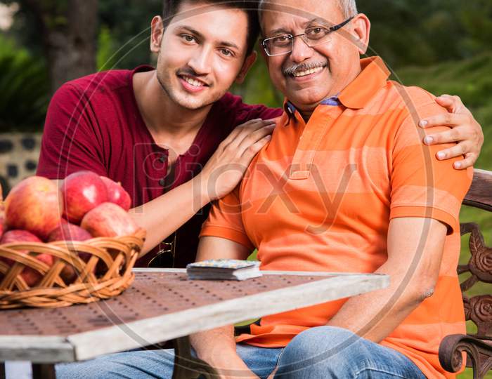 Portrait of Happy Indian/Asian Father and son sitting on lawn chair