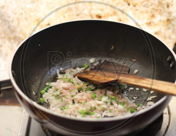Cooking vegetables, onion and green chillies in a fry pan