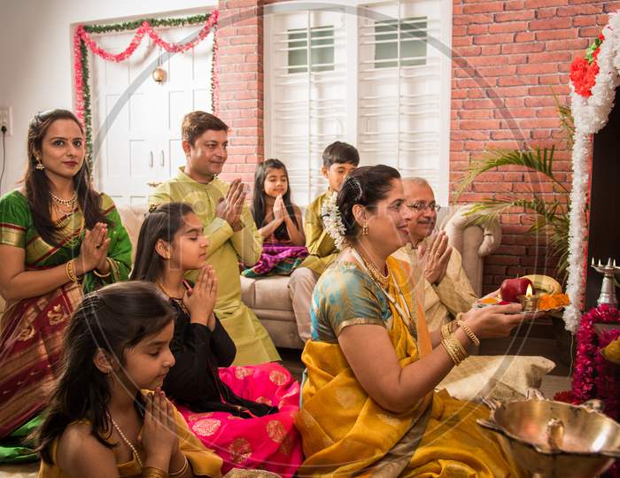 Indian/asian smart family performing Ganesh puja or Aarti at home while wearing traditional wear