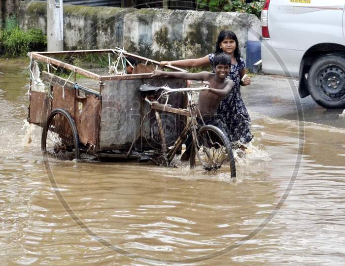 Rag picker children carrying a cart through a waterlogged street