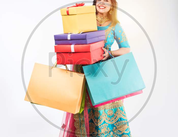 Indian girl with Shopping bags and gift boxes, standing isolated over white background