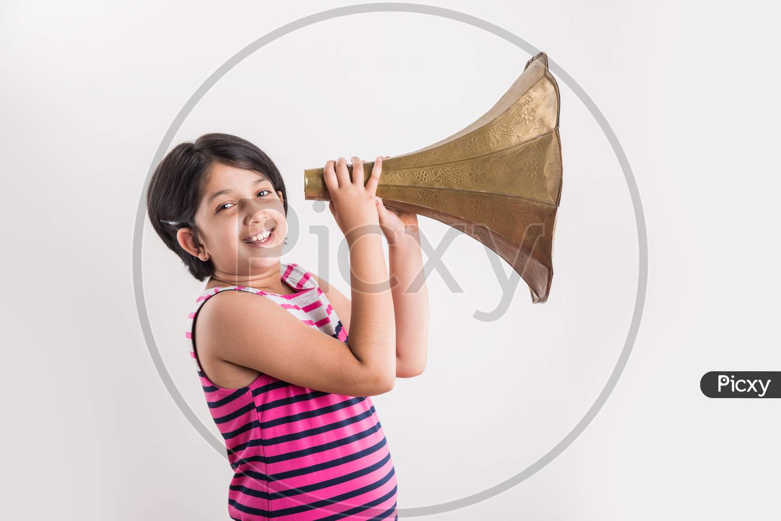 Image of small indian girl shouting / yelling in an vintage brass  gramophone speaker, isolated over white background-BW631223-Picxy
