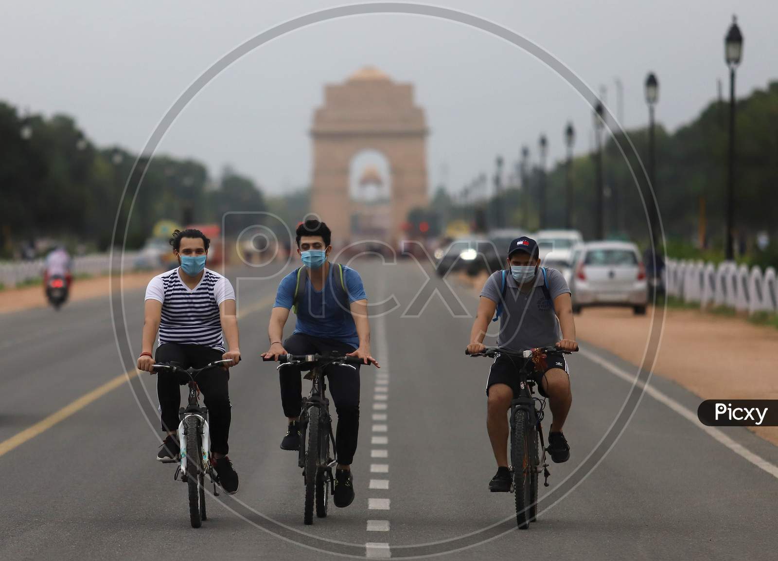 Three men ride their bicycles on Rajpath marg in New Delhi on July 07, 2020