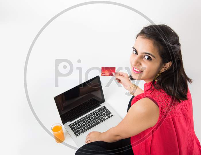 Girl online shopping using debit/credit card on laptop computer