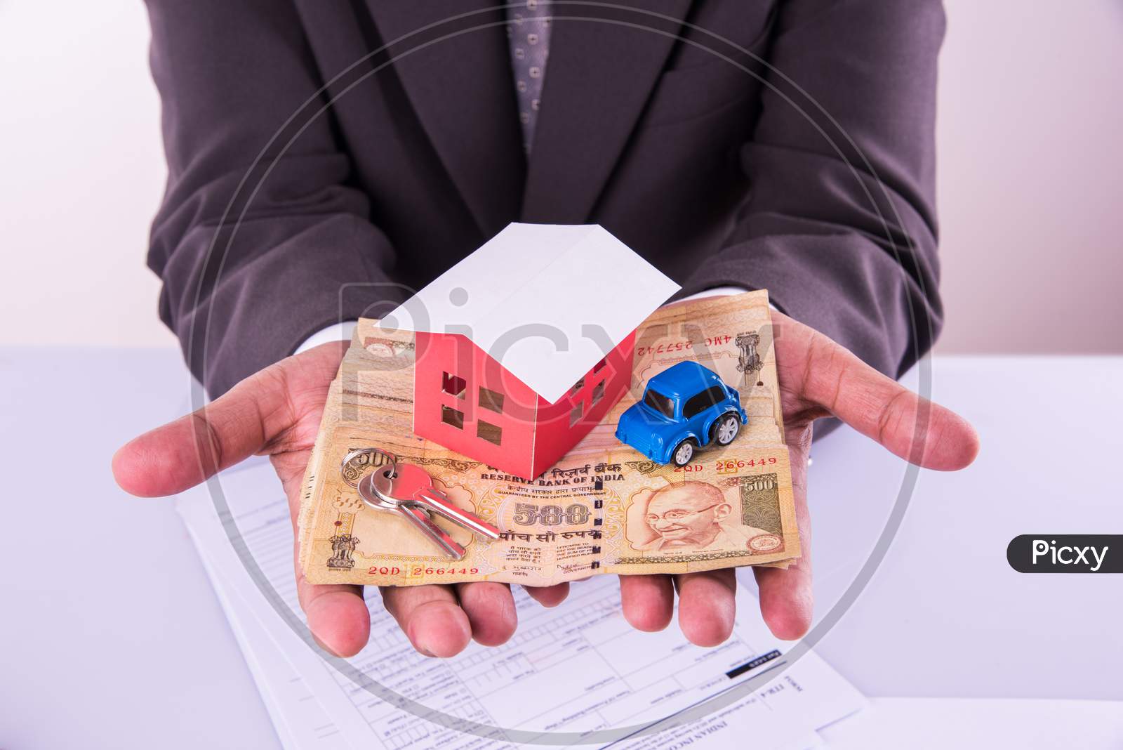 Home and car buying in India - Closeup of indian man holding indian Rupees and 3D home and Car model
