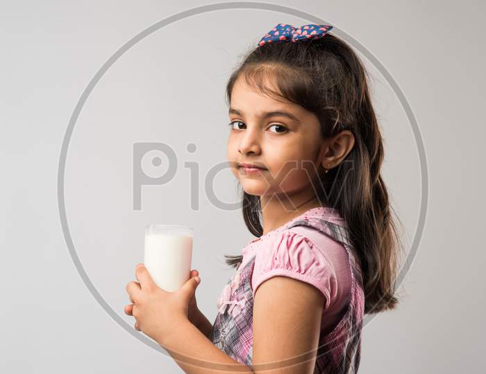 Cute little girl drinking Milk from glass