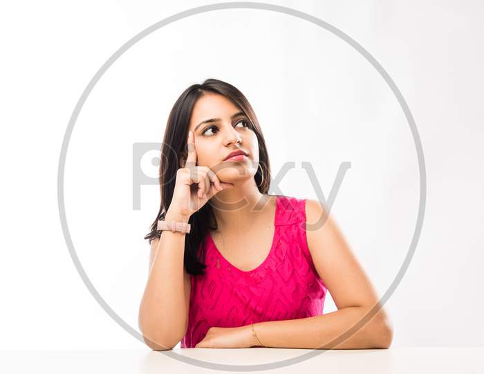Indian girl sitting at table with resting chin on hands