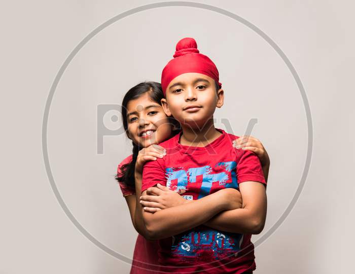 cute little sikh/punjabi boy and girl standing isolated over white background, facing camera