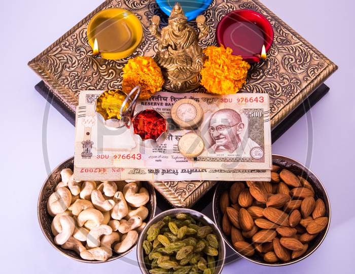 Laxmi Puja with dry fruits, Indian rupees, diya and flower