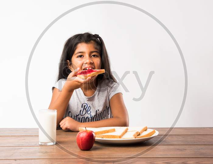 Small Girl eating bread-jam with egg and milk