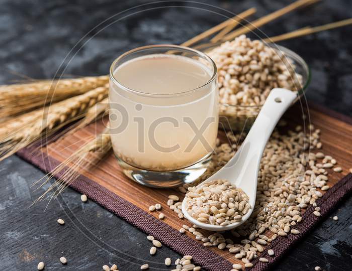 Barley water in glass with raw and cooked pearl barley wheat/seeds