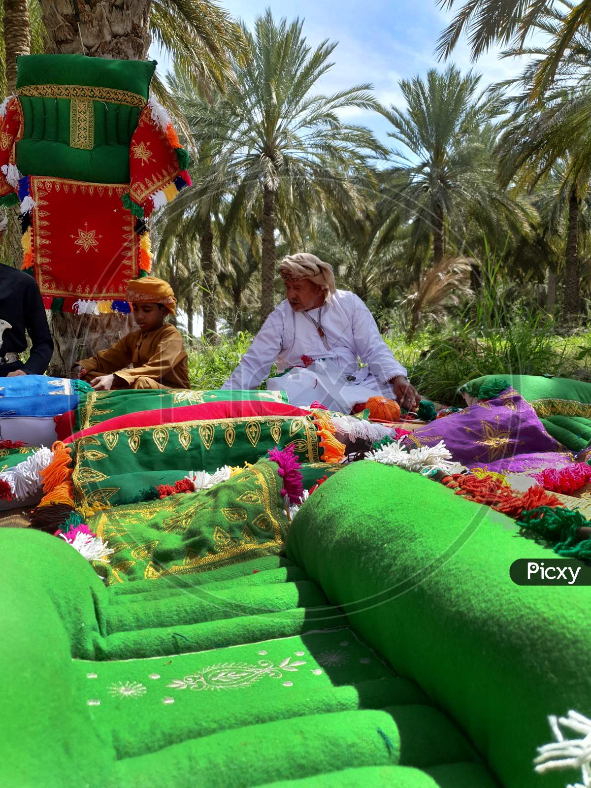 Muscat, Oman 12 july 2020. Old omani man making handmade carpet in the palm garden.