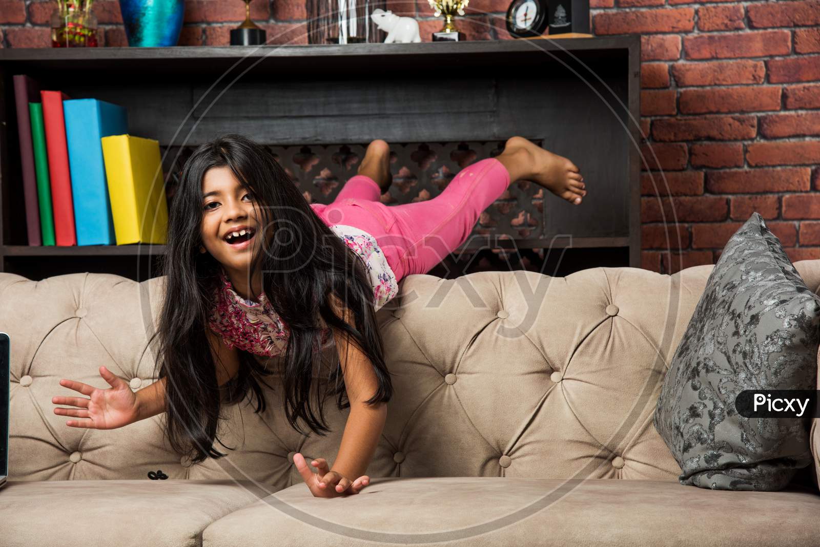 Indian/asian cute little girl jumping on sofa or couch at home