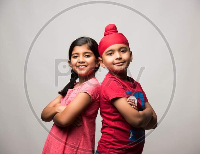 cute little sikh/punjabi boy and girl standing isolated over white background, facing camera