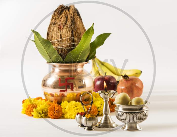 copper kalash with coconut and mango leaf with floral decoration, fruits, diya, sweet pedha,essential in hindu puja, front view,