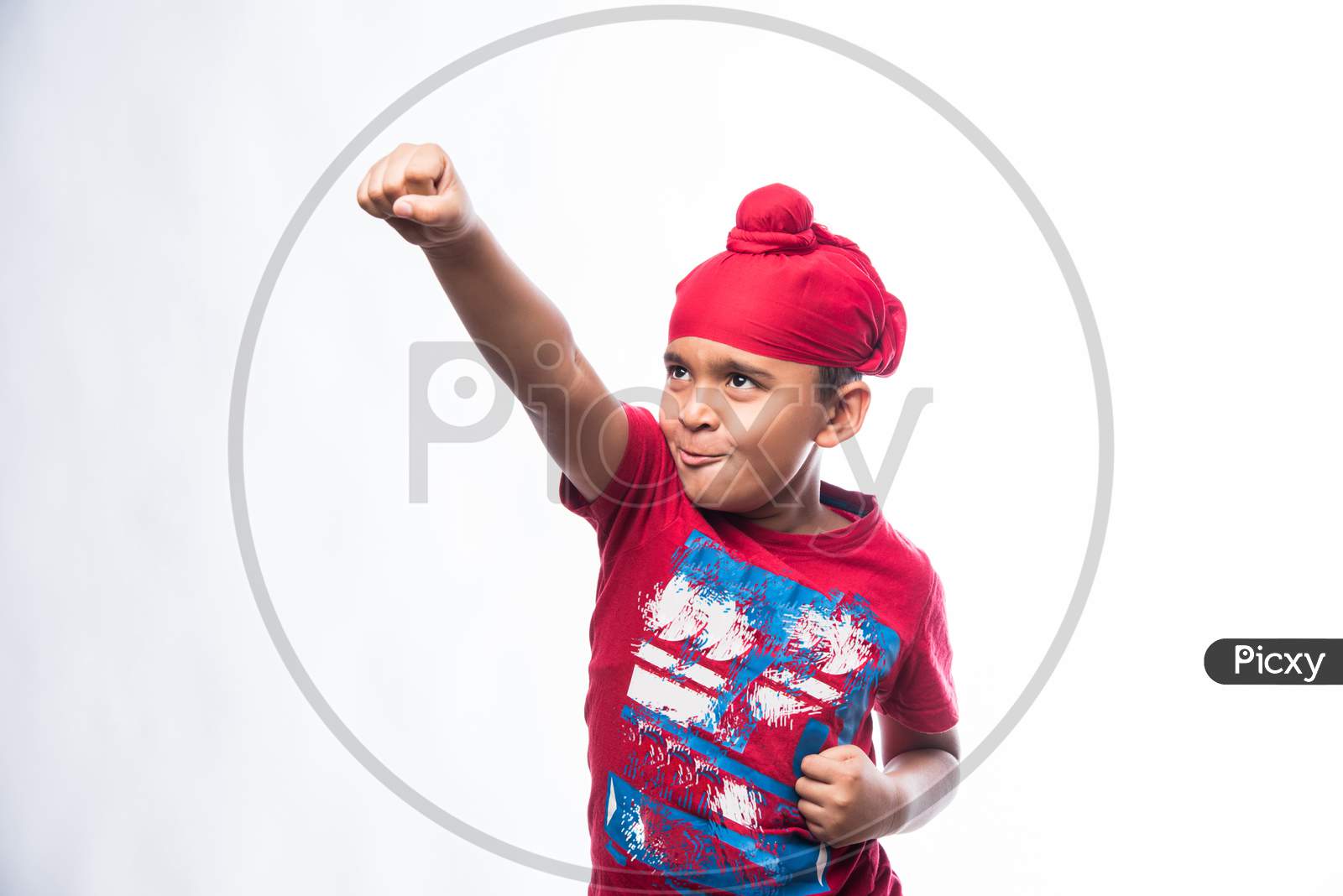 Portrait of Indian Sikh/punjabi little boy showing strength or Karate move while standing isolated over white background